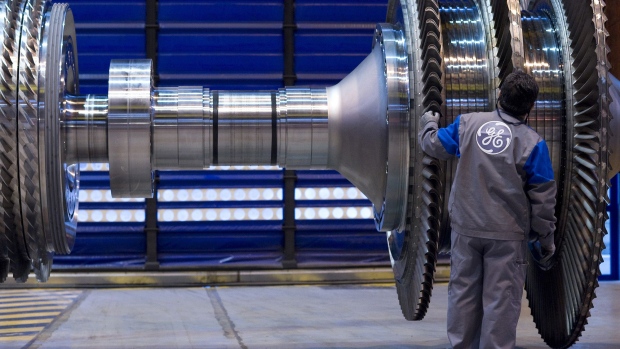 A General Electric Co. employee examines a component for a gas turbine. Photographer: Fabrice Dimier/Bloomberg