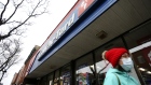 A pedestrian walks in front of a Couche-Tard convenience store.