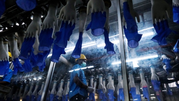 An employee monitors latex gloves on hand-shaped molds moving along an automated production line at a Top Glove Corp. factory in Setia Alam, Selangor, Malaysia, on Tuesday, Feb. 18, 2020. The world’s biggest glovemaker got a vote of confidence from investors in the credit market, as the coronavirus fuels demand for the Malaysian company’s rubber products. The World Health Organization is taking an unprecedented step of negotiating directly with suppliers to improve access to gloves, face masks and other forms of protective equipment. Photographer: Samsul Said/Bloomberg
