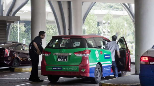 A passenger, left, boards a taxi featuring an advertisement for GrabTaxi, operated by Grab, at the Vivo City taxi stand in Singapore, on Monday, Oct. 31, 2016. Grab is riding a Southeast Asian ride-hailing arena with some 620 million people, forecast to grow more than five times to $13 billion by 2025. Photographer: Ore Huiying/Bloomberg