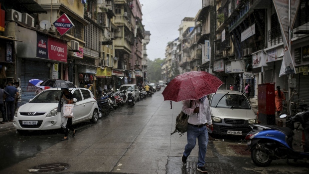 A pedestrian carrying an umbrella walks along a street in the Fort area of Mumbai, India, on Monday, July 6, 2020. The Sensex is headed for a four-month high, even as India overtook Russia to become the country with the third-largest caseload of coronavirus infections. Only the U.S. and Brazil now have more infections than India. Photographer: Dhiraj Singh/Bloomberg