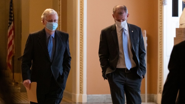 Senate Minority Leader Mitch McConnell, a Republican from Kentucky, left, walks through the U.S. Capitol in Washington, D.C., U.S., on Thursday, Jan. 21, 2021. President Joe Biden is seeking to wipe away Donald Trump's fingerprints from U.S. policy, but his predecessor left lasting partisan divisions in Washington that pose a risk to getting the new president’s agenda through Congress.