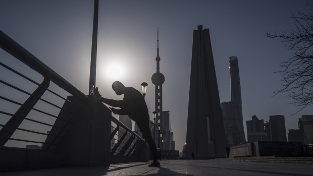 A man stretches on the Bund as skyscrapers of the Pudong Lujiazui Financial District stand across the Huangpu River during sunrise in Shanghai, China, on Friday, March 20, 2020. Most of China is now considered low risk and should return to normal work and life, Premier Li Keqiang said at a government meeting on the coronavirus, which is spreading rapidly in Europe, the U.S. and elsewhere. Photographer: Qilai Shen/Bloomberg