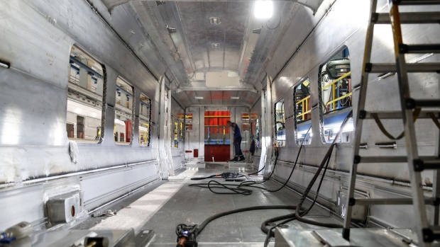 An employee sweeps the internal section of a train carriage ahead of fixture installation at the Stadler Rail AG plant in Bussnang, Switzerland.