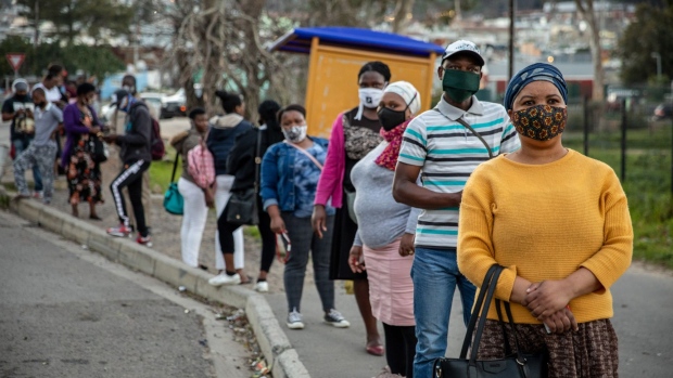 Local residents wearing protective face masks wait at a bus stop in the Imizamo Yethu township area of Hout Bay, in Cape Town, South Africa, on Friday, July 24, 2020. South Africa’s surging coronavirus infections and the resumption of rolling blackouts are clouding the outlook for the economy. Photographer: Dwayne Senior/Bloomberg
