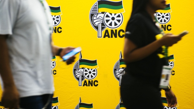 Attendees pass by ANC branded boarding during the 54th national conference of the African National Congress party in Johannesburg, South Africa, on Sunday, Dec. 17, 2017. The leadership conference of South Africa’s ruling African National Congress party has accepted the credentials of the delegates, opening the way for the start of voting to choose the party’s top officials, according to five people familiar with the deliberations. Photographer: Waldo Swiegers/Bloomberg