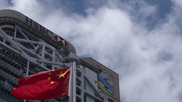 The flag of China flies near the HSBC Holdings Plc building, left, and the Standard Chartered Plc building in Hong Kong, China, on Thursday, June 4, 2020. HSBC and Standard Chartered, the two British institutions that dominate Hong Kong's banking system, backed Beijing in the standoff over a proposed new security law, joining Jardine Matheson Holdings Ltd. and some of the city's biggest developers in wading into the political minefield of the former colony's future. Photographer: Roy Liu/Bloomberg