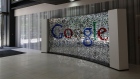 A visitor passes a sign featuring Google Inc.'s logo inside their U.K. headquarters at Six St Pancras Square in London.