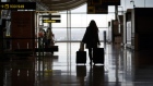 A passenger wheels a suitcase through a deserted arrivals hall at Madrid Barajas airport, in Madrid.