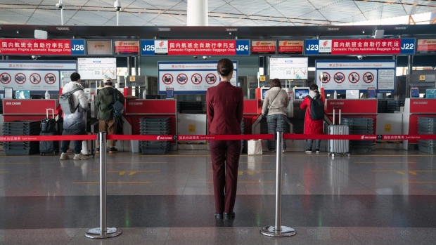 A staff stands in front of Air China Ltd. baggage drop counters for domestic flights at Beijing Capital International Airport ahead of Lunar New Year in Beijing, China, on Tuesday, Feb. 2, 2021. China expects a sharp downturn in travel over the Lunar New Year period compared with pre-pandemic levels following new restrictions to control coronavirus outbreaks, threatening a nascent-recovery in consumer spending.