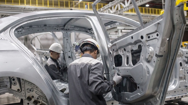 Workers attach rear doors to the body frame of a Vinfast Lux A2.0 sedan as it moves along a conveyor in the body shop area of the automaker's factory in Haiphong, Vietnam, on Wednesday, Dec. 4, 2019.