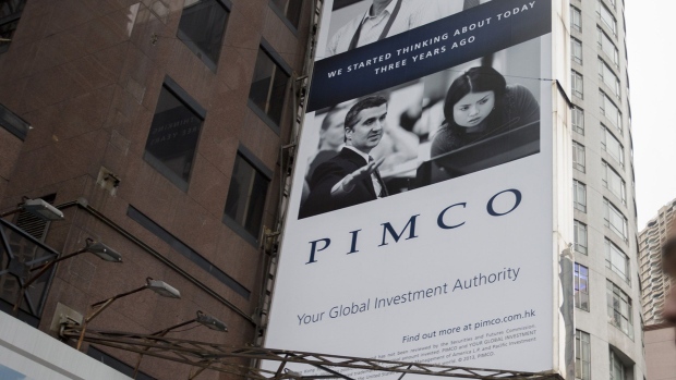 A man walks past a Pacific Investment Management Company LLC (PIMCO) advertisement which is displayed on a building in Hong Kong, China. Photographer: Brent Lewin/Bloomberg