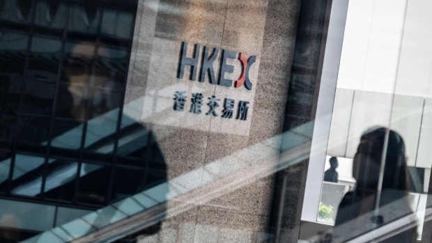 People wearing protective masks walk past signage for Hong Kong Exchanges & Clearing Ltd. (HKEX) displayed at the Exchange Square complex in Hong Kong, China, on Wednesday, Aug. 19, 2020. Photographer: Roy Liu/Bloomberg