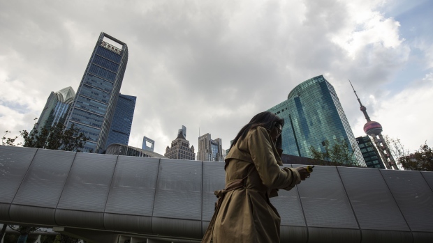 A woman walks past a footbridge as skyscrapers stand in the Pudong Lujiazui Financial District in Shanghai, China, on Tuesday, Nov. 13. 2018. Photographer: Qilai Shen/Bloomberg