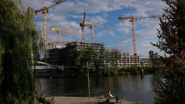 Construction cranes stand above the Europacity project residential building site as a fisherman sits beside his rod on the bank of the River Spree in Berlin, Germany, on Wednesday, June 27, 2018. In a rough-and-tumble corner of former communist east Berlin, Canadian rocker Bryan Adams is turning a downtrodden industrial site along the Spree river into exclusive artist studios. Photographer: Krisztian Bocsi/Bloomberg