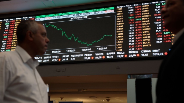 People pass by an electronic board displaying stock activity at the Brasil Bolsa Balcao (B3) stock exchange in Sao Paulo, Brazil, on Thursday, March 21, 2019. Brazil's Ibovespa Index fell Thursday following the arrest of former Brazilian president Michel Temer as part of the Carwash corruption probe that's ensnared some of the country's top business executives and politicians. Photographer: Patricia Monteiro/Bloomberg