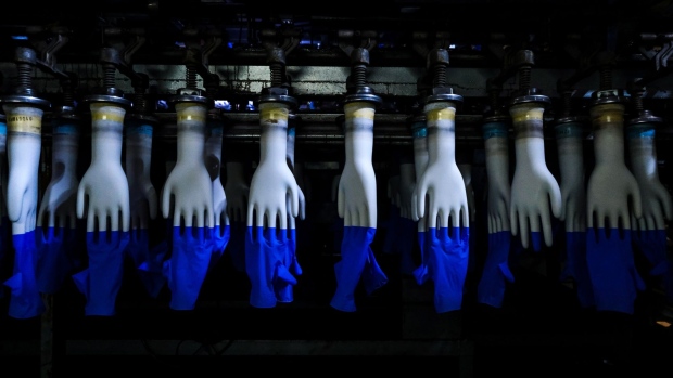 Latex gloves on hand-shaped molds move along an automated production line at a Top Glove Corp. factory in Setia Alam, Selangor, Malaysia, on Tuesday, Feb. 18, 2020. The world’s biggest glovemaker got a vote of confidence from investors in the credit market, as the coronavirus fuels demand for the Malaysian company’s rubber products. The World Health Organization is taking an unprecedented step of negotiating directly with suppliers to improve access to gloves, face masks and other forms of protective equipment. Photographer: Samsul Said/Bloomberg