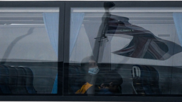 A British Union flag, also known as Union Jack, is reflected in a coach window as it arrives with travelers to stay in quarantine at the Radisson Blu Edwardian hotel at London Heathrow Airport in London, U.K., on Monday, Feb. 15, 2021. Some passengers traveling to the U.K. will face tougher quarantine measures, including enforced stays in hotels, repeated tests, and the threat of fines and even jail.