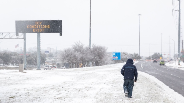 A pedestrian walks past a road sign warning commuters of icy conditions on a road in Austin, Texas, U.S., on Thursday, Feb. 18, 2021. Texas is restricting the flow of natural gas across state lines in an extraordinary move that some are calling a violation of the U.S. Constitution’s commerce clause. Photographer: Thomas Ryan Allison/Bloomberg
