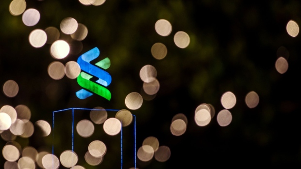 Signage is illuminated atop the Standard Chartered Bank building at night in Hong Kong, China, on Thursday, July 25, 2019. Standard Chartered is scheduled to release interim earnings results on Aug. 1.