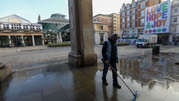 A municipal worker cleans the street near the Christmas tree in the Covent Garden district of London, U.K., on Thursday, Nov. 5, 2020. The Bank of England boosted its bond-buying program by a bigger-than-expected 150 billion pounds ($195 billion) in another round of stimulus to help the economy through a second wave of coronavirus restrictions. Photographer: Chris Ratcliffe/Bloomberg