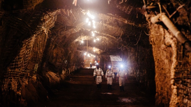 Miners shine head torches as they walk through an underground tunnel at the South Deep gold mine, operated by Gold Fields, in Westonaria, South Africa.