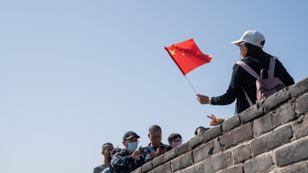A visitor holds a Chinese flag while posing for a photograph at the Badaling section of the Great Wall in Beijing, China, on Thursday, Oct. 1, 2020. China's so-called Golden Week holiday this year starts with the Mid-Autumn Festival and National Day on Thursday and runs to Oct. 8. Photographer: Yan Cong/Bloomberg