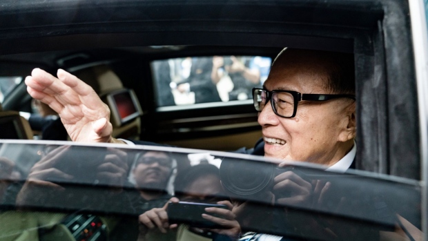 Li Ka-shing, former chairman and senior adviser of CK Hutchison Holdings Ltd. and CK Asset Holdings Ltd., waves from his car as he leaves the companies' annual general meetings in Hong Kong, China, on Thursday, May 10, 2018. The 89-year-old tycoon, who announced his retirement plans in March, resigned as chairman of the two companies today. His eldest son, 53-year-old Victor Li, will take over.
