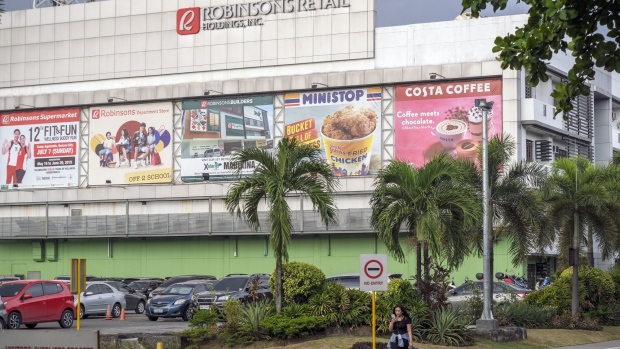 A pedestrian walks in front of the Robinsons Retail Holdings Inc., head offices in Manila, the Philippines, on Friday, June 21, 2019. Robinsons Retail is considering an exit from the fashion business as it struggles to compete with cheaper, faster chains like Fast Retailing Co.’s Uniqlo. Photographer: Veejay Villafranca/Bloomberg