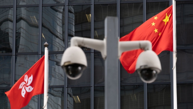 The flags of China, right, and the Hong Kong Special Administrative Region (HKSAR) are flown behind a pair of surveillance cameras outside Central Government Offices in Hong Kong, China, on Tuesday, July 7, 2020. Hong Kong leader Carrie Lam defended national security legislation imposed on the city by China last week, hours after her government asserted broad new police powers, including warrant-less searches, online surveillance and property seizures. Photographer: Roy Liu/Bloomberg