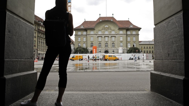 A pedestrian looks towards the Swiss National Bank (SNB) building in Bern, Switzerland, on Wednesday, June 6, 2018. Up for a national vote on Sunday is a measure that would upend the way financial institutions do business by forbidding banks from "creating" money through lending.