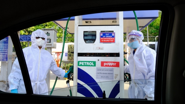 Employees wearing personal protective equipment (PPE) are seen through a window of a customer's vehicle at a Hindustan Petroleum Corp. gas station during a lockdown imposed due to the coronavirus in New Delhi, India, on Monday, April 27, 2020. Oil has lost almost 80% this year as global efforts to stem the spread of the coronavirus vaporized demand for everything from gasoline to crude. The world's biggest producers have pledged to slash daily output from the start of next month to try and balance the market, but the collapse in consumption has led to a swelling glut that's testing the limits of storage worldwide. Photographer. T. Narayan/Bloomberg