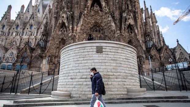 A pedestrian wearing a protective face mask passes along a deserted road outside the Sagrada Familia cathedral in Barcelona.