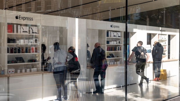 Customers wear protective masks while standing inside an Apple Inc. store in San Francisco.