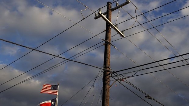The U.S. and Texas flags fly next to a power pole on February 21, 2021 in Houston.
