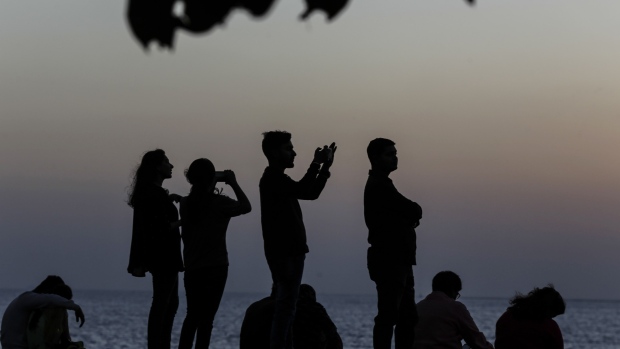 People take photographs at Marine Drive at sunset in Mumbai, India, on Monday, March 9, 2020. India's central bank seizing control of beleaguered Yes Bank Ltd. last week intensified the risk-off mood fueled by the spread of coronavirus cases in India. Photographer: Dhiraj Singh/Bloomberg