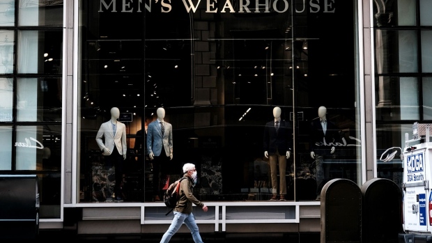 Men's business attire is displayed in the window of a store.