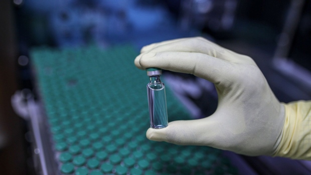 An employee holds up a vial of Covishield, the local name for the Covid-19 vaccine developed by AstraZeneca Plc. and the University of Oxford, arranged on the production line at the Serum Institute of India Ltd. Hadaspar plant in Pune, Maharashtra, India, on Friday, Jan. 22, 2021. Serum, which is the world's largest vaccine maker by volume, has an agreement with AstraZeneca to produce at least a billion doses. Photographer: Dhiraj Singh/Bloomberg