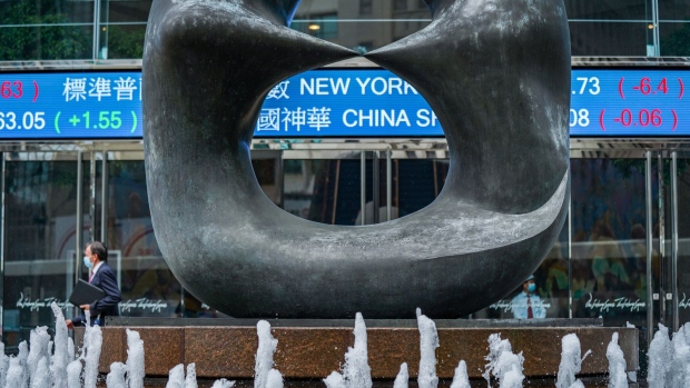 A sculpture stands in front of a stock ticker at the Exchange Square complex, which houses the Hong Kong Stock Exchange, in Hong Kong, China, on Friday, May 29, 2020. The struggle to maintain confidence in Hong Kong's future is manifesting in its stock and currency markets.