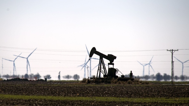 An oil pump jack in a field with wind turbines in Corpus Christi, Texas, U.S., Friday, Feb. 19, 2021. Natural gas futures fluctuated Friday as an energy crisis plaguing the central U.S. eased amid an outlook for milder weather and a decline in blackouts. Photographer: Eddie Seal/Bloomberg