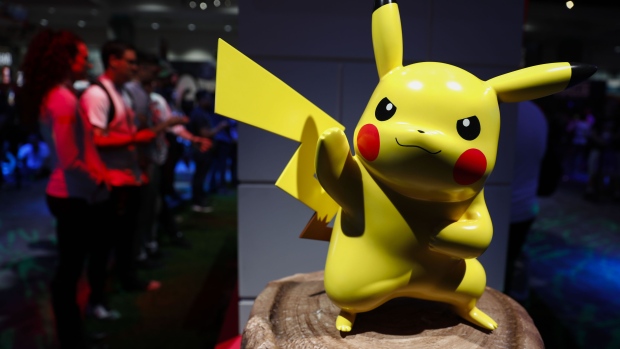 A Pikachu statue stands as attendees play Nintendo Co. Pokemon: Let's Go Pikachu! video game at the company's booth during the E3 Electronic Entertainment Expo in Los Angeles, California, U.S., in Los Angeles, California, U.S., on Wednesday, June 13, 2018. For three days, leading-edge companies, groundbreaking new technologies and never-before-seen products are showcased at E3. Photographer: Patrick T. Fallon/Bloomberg