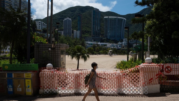 A pedestrian wearing a protective mask walks past a closed Repulse Bay beach in Hong Kong, China, on Tuesday, July 28, 2020. Hong Kong has been taken off-guard by the sudden jump of infections after managing to contain the spread locally as it tore across the world. Officials are now scrambling to slow what they're calling a third wave, while boosting health-care facilities that are reaching capacity.