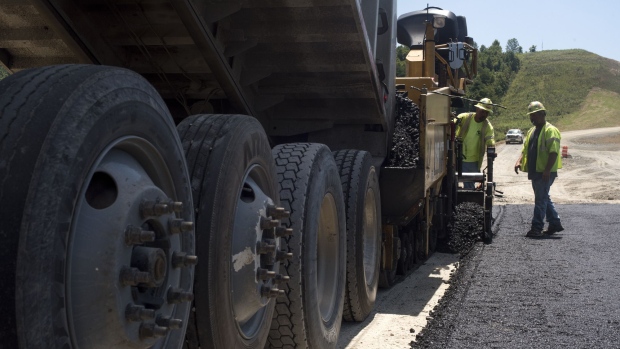 A truck dumps asphalt as contractors pave a road during highway construction between U.S. Route 23 and U.S. Route 52 near Portsmouth, Ohio, U.S., on July 26, 2017. The U.S. Census Bureau is scheduled to release construction spending figures on August 1. Photographer: Ty Wright/Bloomberg