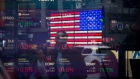 Monitors display stock market information as pedestrians are reflected in a window at the Nasdaq MarketSite in the Times Square area of New York, U.S., on Friday, April 26, 2019. U.S. stocks edged higher on better-than-forecast earnings while Treasury yields fell after data signaled tepid inflation in the first quarter. Photographer: Michael Nagle/Bloomberg