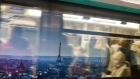 Morning rush hour commuters wear protective face masks while passing a poster showing the Eiffel Tower and city skyline at Champs-Elysees–Clemenceau metro station in Paris, France, on Wednesday, Oct. 14, 2020. After putting six cities including Paris on maximum alert, President Macron Macron may announce additional restrictions on French national television today. Photographer: Nathan Laine/Bloomberg
