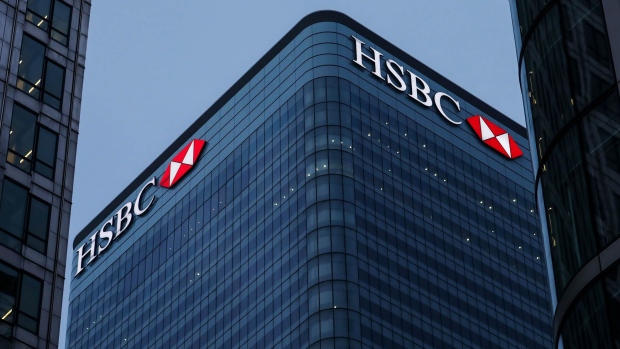 Logos sit illuminated on the HSBC Holdings Plc headquarter skyscraper offices in the Canary Wharf business, financial and shopping district in London, U.K., on Tuesday, May 2, 2017. HSBC has appeased investors with $3.5 billion of share buybacks, but after five years of declining revenue analysts are looking for evidence the bank is stabilizing its top line when it reports earnings Thursday.