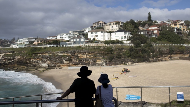 A silhouetted couple at the beach stand near houses in the Tamarama suburb of Sydney, Australia, on Saturday, Feb. 20, 2021. Australia's housing market is booming again, with the biggest monthly price gain in 17 years dispelling fears of a Covid-induced downturn. Photographer: Brent Lewin/Bloomberg