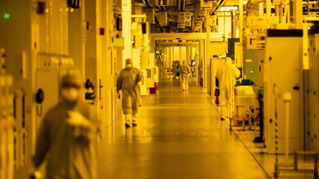 Employees wearing cleanroom suits walk through the main bay inside the GlobalFoundries semiconductor manufacturing facility in Malta, New York, U.S., on Tuesday, March 16, 2021. Production plants for semiconductors have become a focal point as the economic recovery from the pandemic is held back in areas by a shortage of some of the critical electronic components necessary.