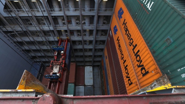 A pair of shipping containers hang from a ship-to-shore crane as the hull of container ship Guayaquil Express, operated by Hapag-Lloyd AG, is unloaded at the HLA Container Terminal Altenwerder (CTA) in the port of Hamburg in Hamburg.