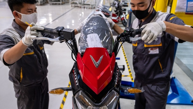 Workers labor on a VinFast Impes electric scooter on the assembly line of the automaker's factory in Haiphong, Vietnam, on Wednesday, Sept. 16, 2020. Vietnamese billionaire Pham Nhat Vuong, the founder and chairman of Vingroup JSC, wants to help his nation’s 96 million motorbike riders go green, replacing their noisy gas guzzlers with electric scooters. Subsidiary VinFast has a new $3.5 billion, 36.1 million-square-foot factory in Haiphong, where it’s building e-scooters, electric buses, and electric cars.